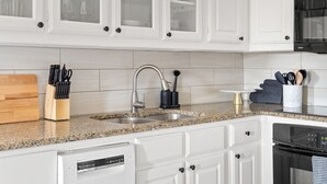 A modern kitchen with white cabinetry, granite countertops, a stainless steel sink, and a built-in dishwasher. - Artsy urban retreat steps from Bishop Arts. Thoughtfully designed with creative touches, a dreamy coffee station, and a king bed you won't want to leave. Gated parking and a responsive host. Repeat guests say it's even more beautiful in person. (Dallas)