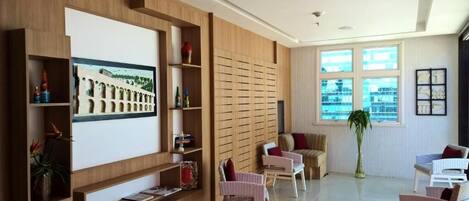 A modern interior with a wooden wall, a large framed picture, wicker chairs, and a potted plant.