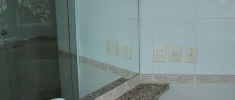 A bathroom with a granite countertop, a white sink, a toilet, and a glass shower enclosure.