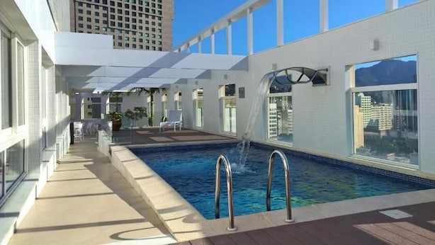 An indoor swimming pool with clear blue water, metal pool ladders, and a tiled deck. - Hotel Atlântico Tower - SOFT OPENING (Rio de Janeiro)