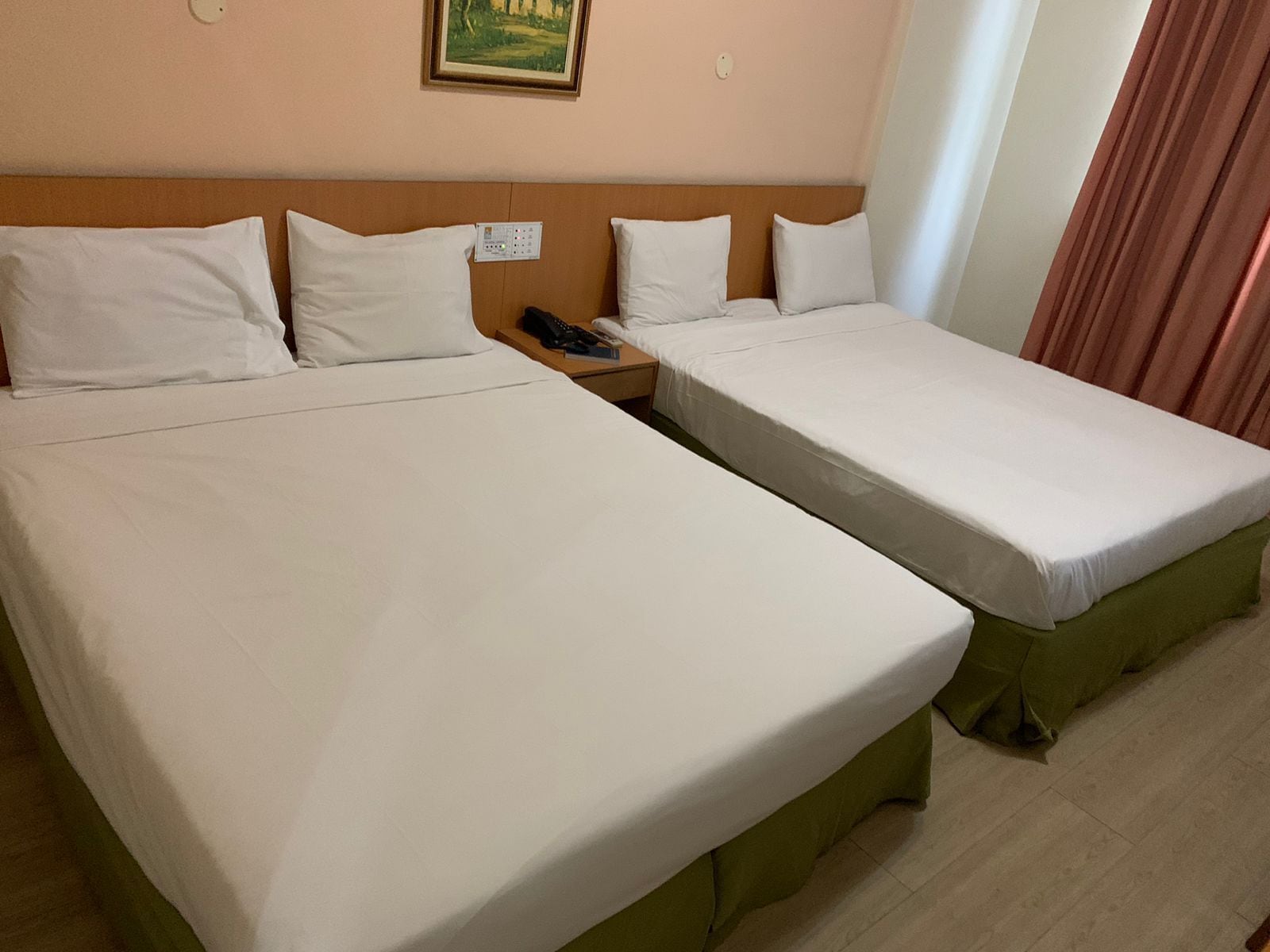 Ein Hotelzimmer mit zwei Einzelbetten, einem Nachttisch mit Telefon und einem Bild an der Wand.