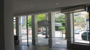 A hotel lobby with large glass doors leading to a street view. - Hotel Atlântico Tower - SOFT OPENING (Rio de Janeiro)