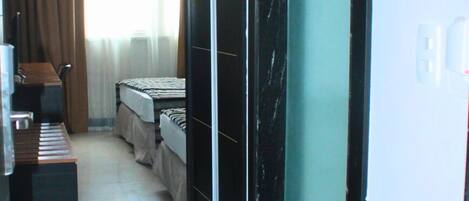 A hotel corridor with a bed, a desk, and a chair.