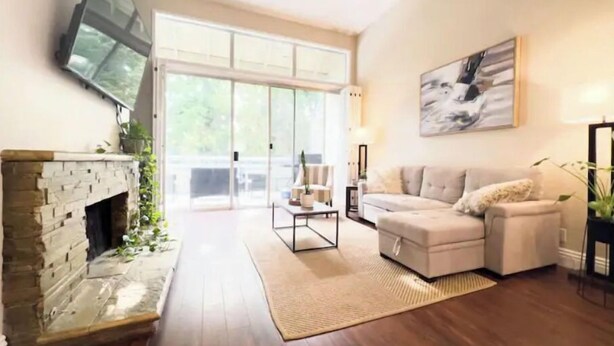 Una sala de estar con chimenea, un sofá, una mesa de centro y un televisor instalado en la pared.