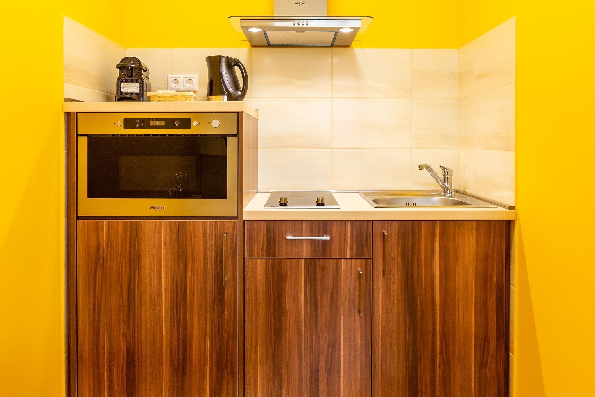 A compact kitchen with a built-in oven, a coffee maker, and a sink.