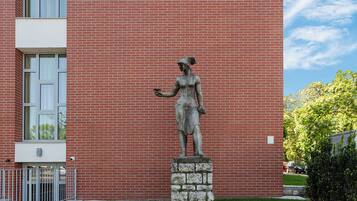 A brick building with a sign reading "Superior Hostel Mayer" and a statue of a woman in front.