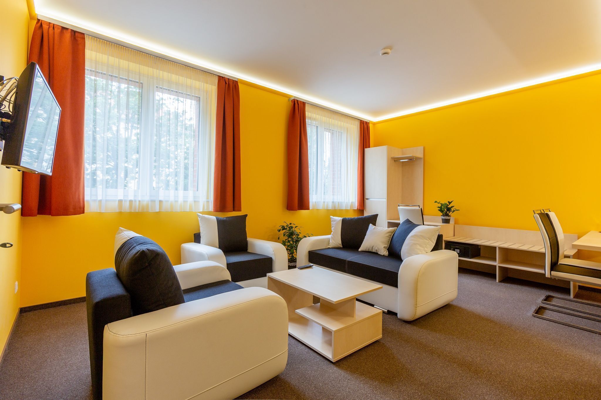 A modern living room with a yellow wall, white sofas, and a coffee table.