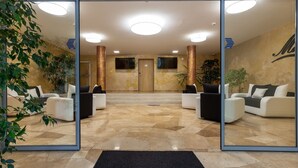 A modern lobby with a glass entrance, a reception desk, and seating areas. - Hostel Mayer Superior Veszprém (Veszprem)