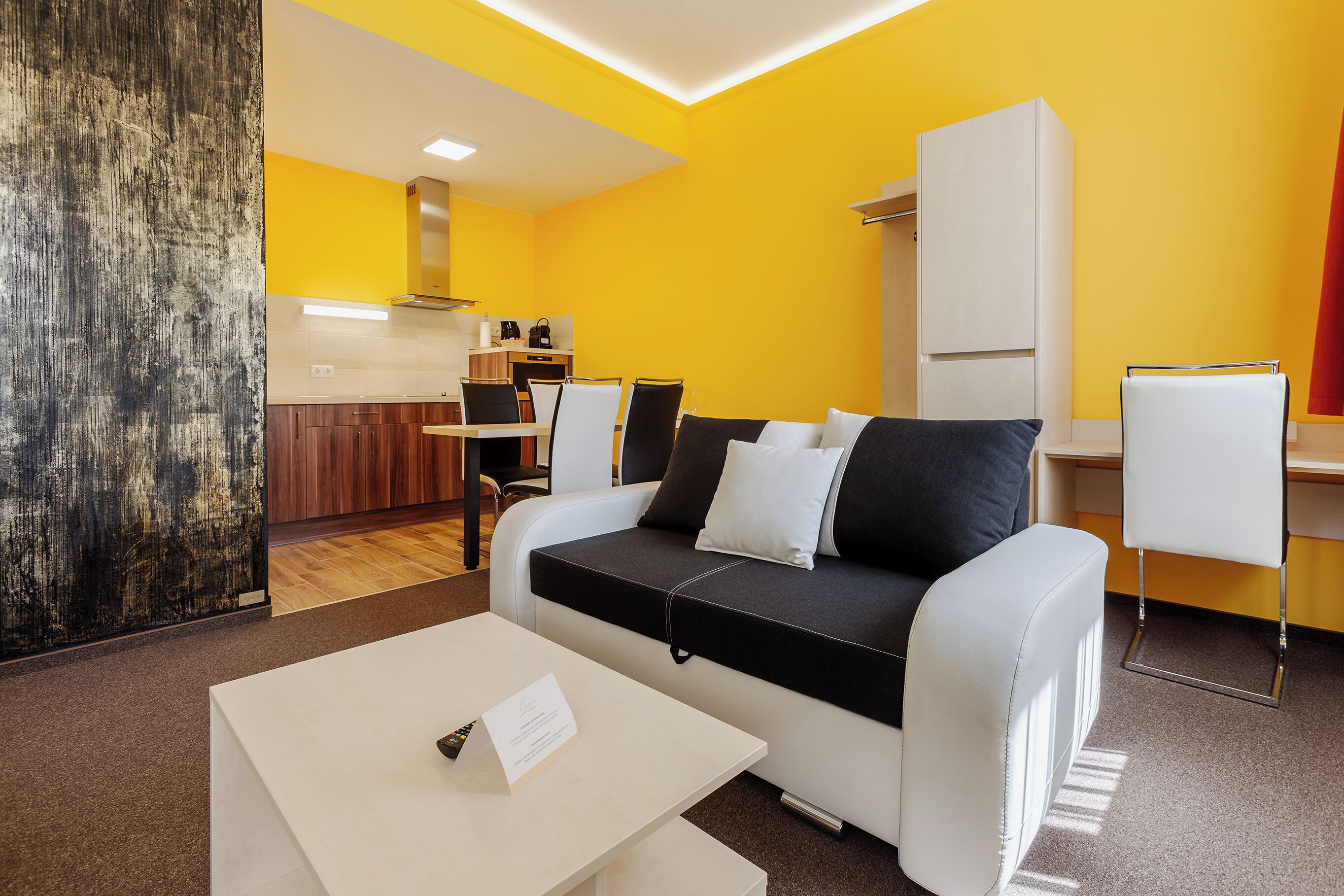 A modern living room with a sofa, a coffee table, and a dining area.