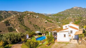 Una villa bianca con piscina, immersa nel verde e circondata da colline.
