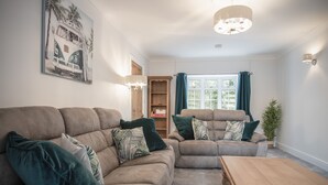 A living room with two sofas, a wooden coffee table, and a painting of a vintage car.