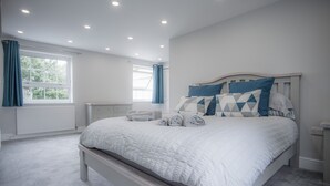 A bedroom with a large bed, a window with curtains, a radiator, and a bedside table.