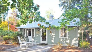 A small, single-story building with a porch, two white chairs, and a sign reading "Bleedmore 5990". - Charming, Updated Home in the Heart of Downtown Glen Arbor!  (Glen Arbor)