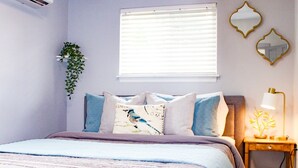 A bedroom with a bed, bedside table, lamp, and wall decorations. - Stay near Point Defiance Park in our charming 1-bedroom cottage (Tacoma)