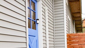 A house with a blue door, a wooden fence, and a large orange vase on the porch. - Stay near Point Defiance Park in our charming 1-bedroom cottage (Tacoma)
