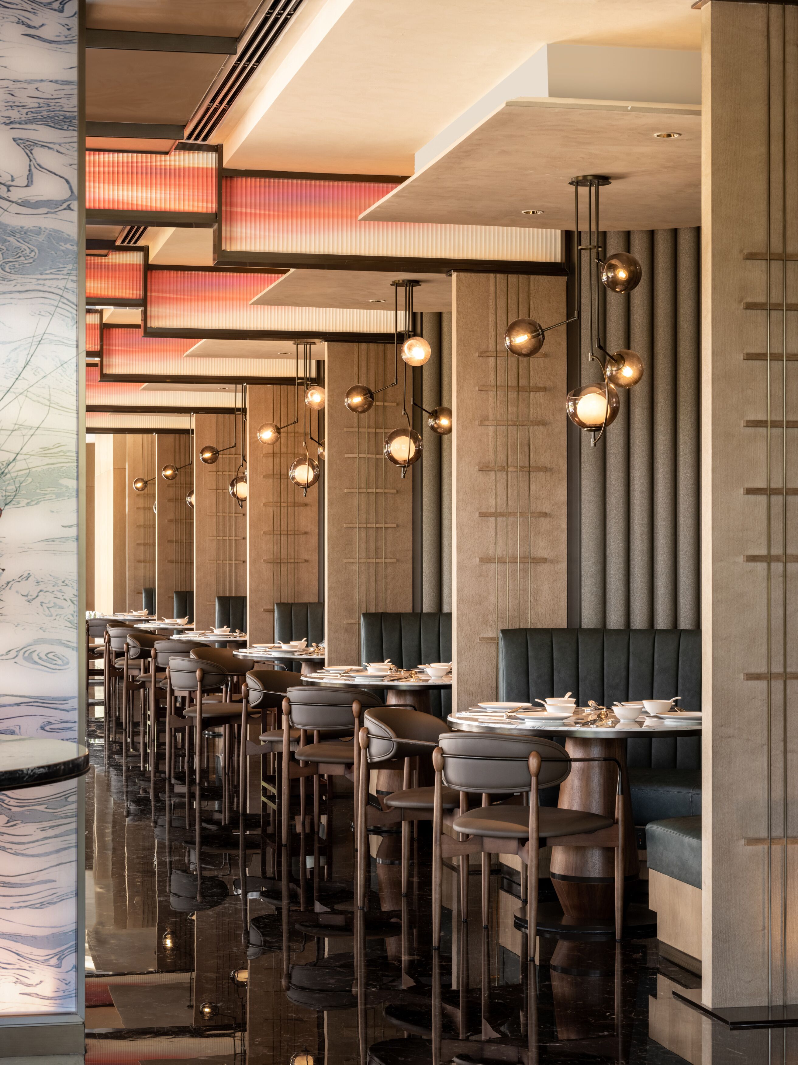 A modern restaurant interior with high ceilings, pendant lighting, and a polished floor.