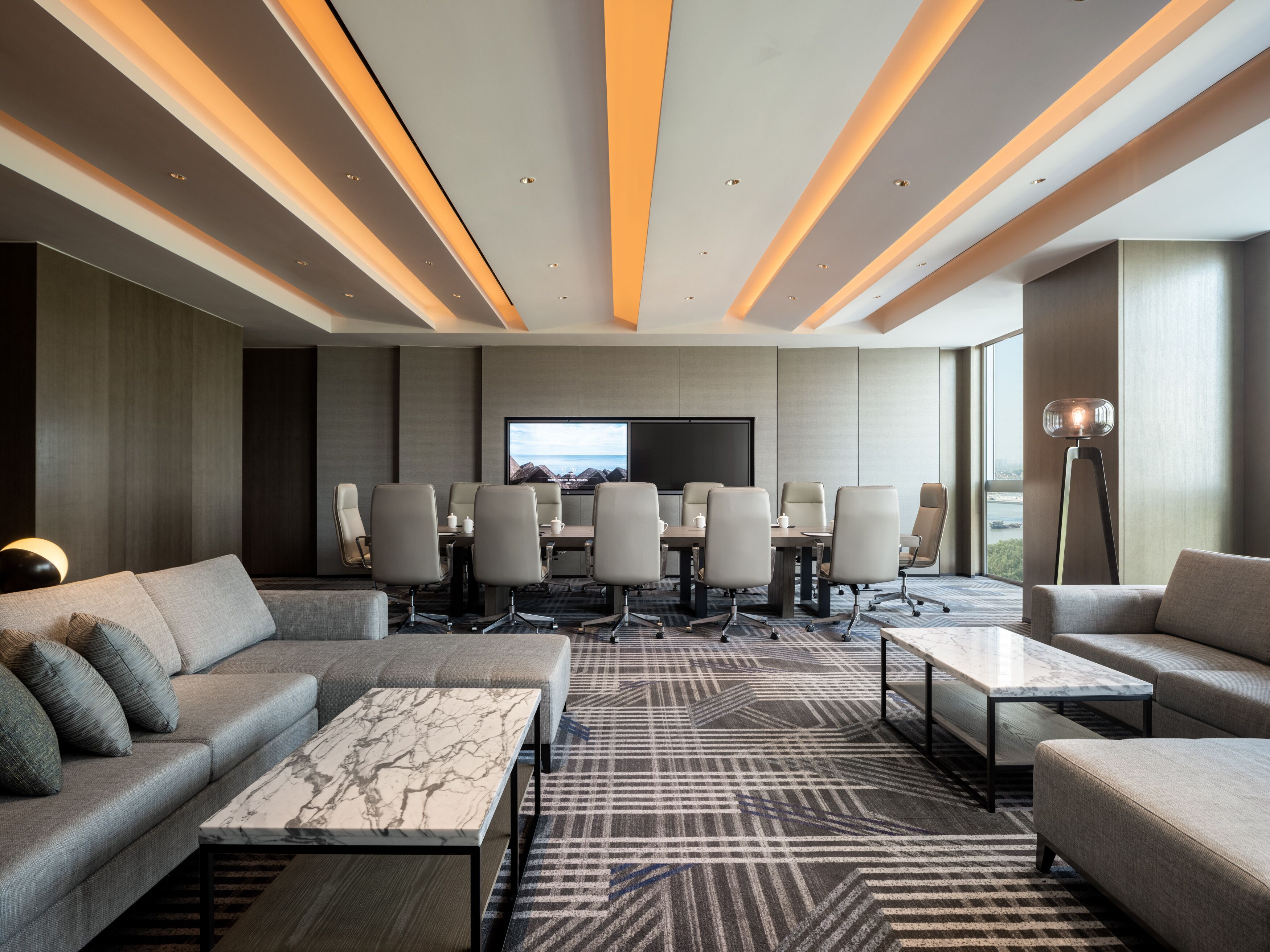 A modern conference room with a large TV screen, multiple chairs, and a sofa.