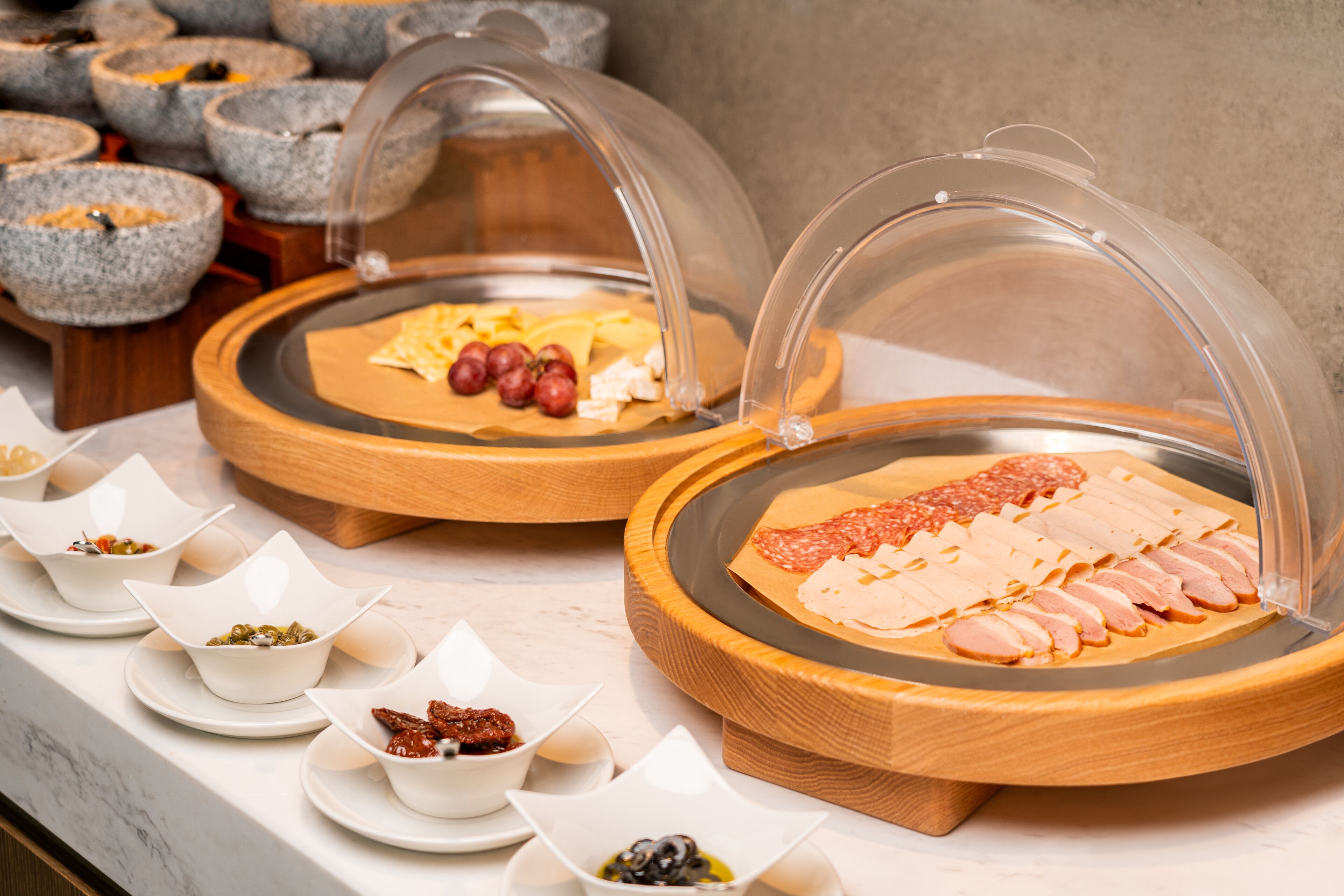 Un buffet proposant une variété de plats présentés sur des planches en bois et protégés par des cloches en verre.