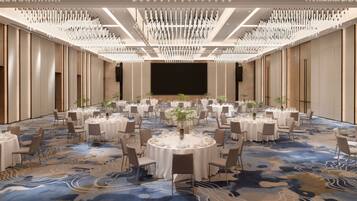 A large conference room with round tables, chairs, and a stage.