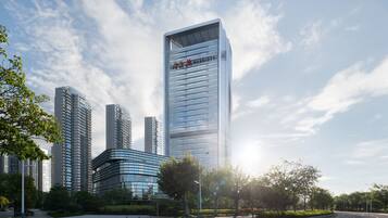 A modern high-rise hotel with a prominent 'Marriott' sign, surrounded by other tall buildings and greenery.