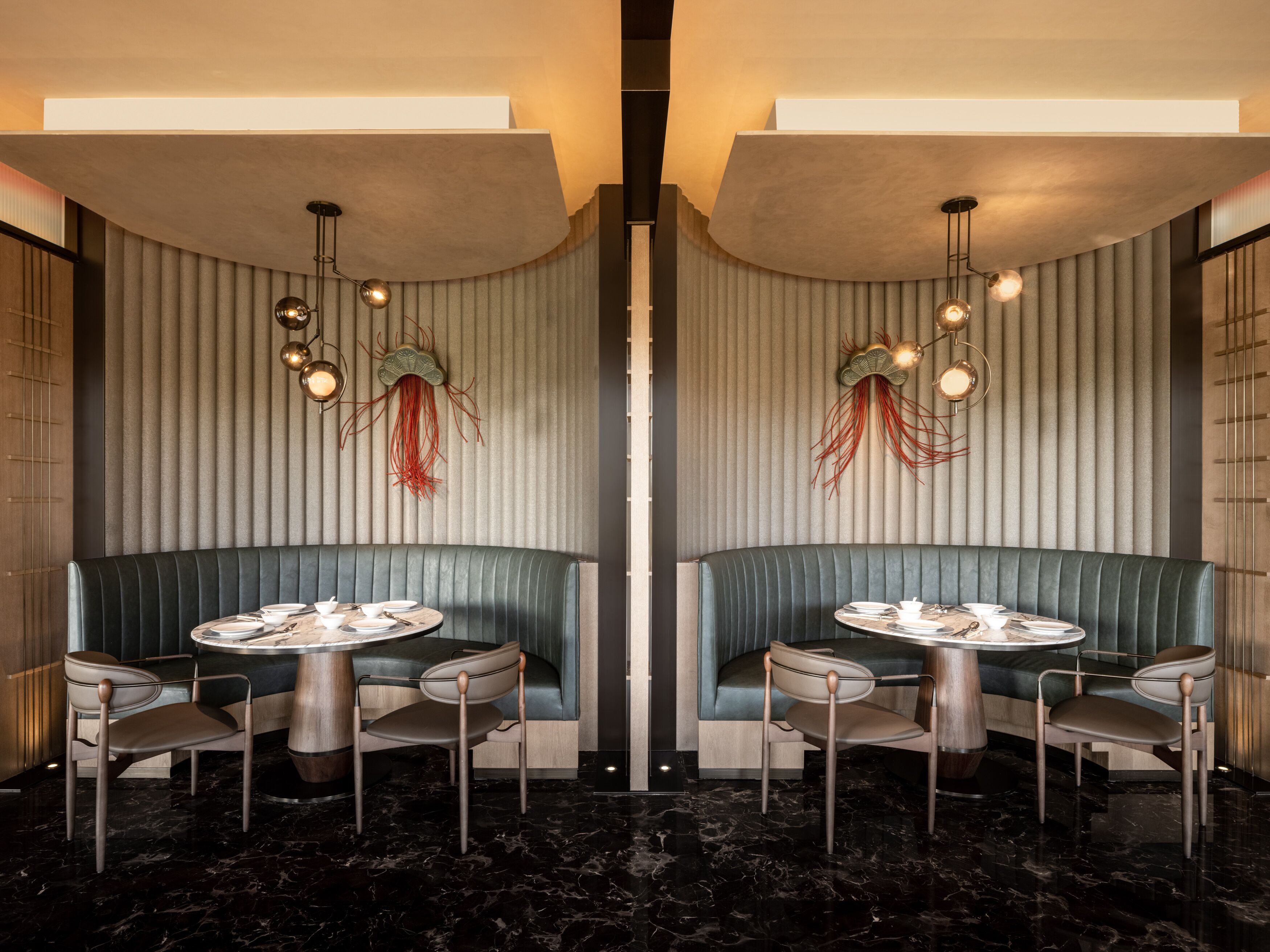 Un salón con espejos, dos cabinas verdes, mesas redondas e iluminación moderna.