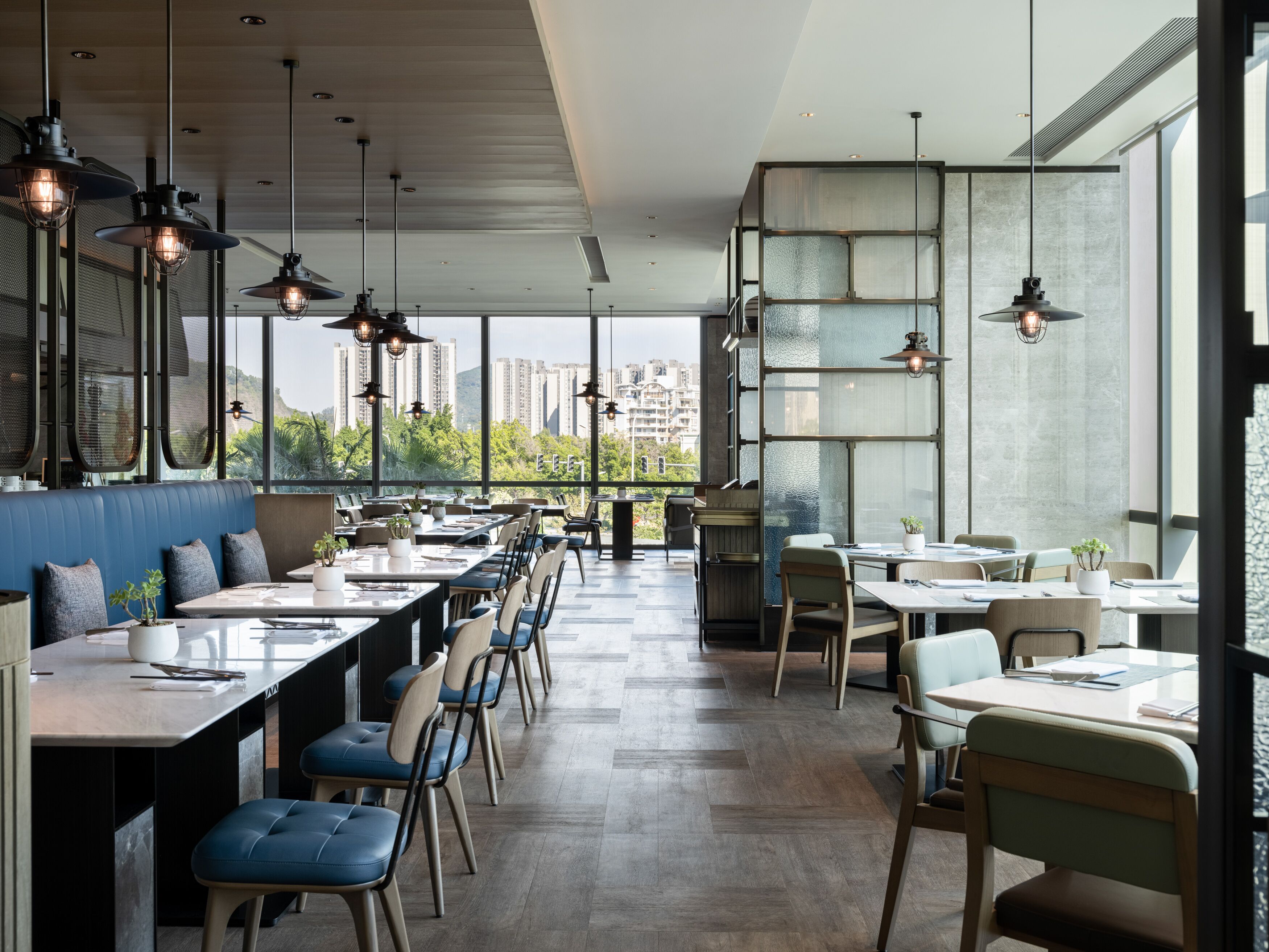 A modern restaurant with high ceilings, large windows, and a view of the cityscape.