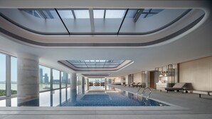 Una piscina interior moderna con tragaluces, zonas de descanso y vistas a la ciudad.