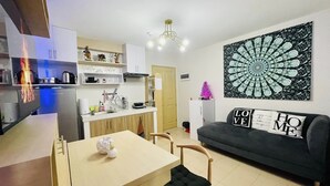 A modern kitchen with white cabinets, a dining table with chairs, and a black and white patterned wall hanging.