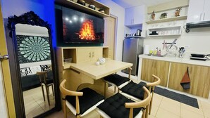 A compact living space with a TV, wooden furniture, and a kitchen area.