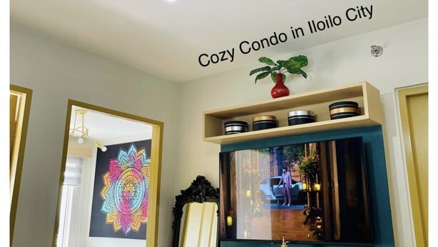 A cozy living room with a ceiling light fixture, a flat-screen TV, and a decorative mirror.
