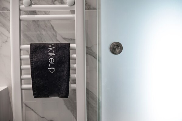 A towel hanging on a white towel rack in a bathroom with a marble floor and a light blue door.