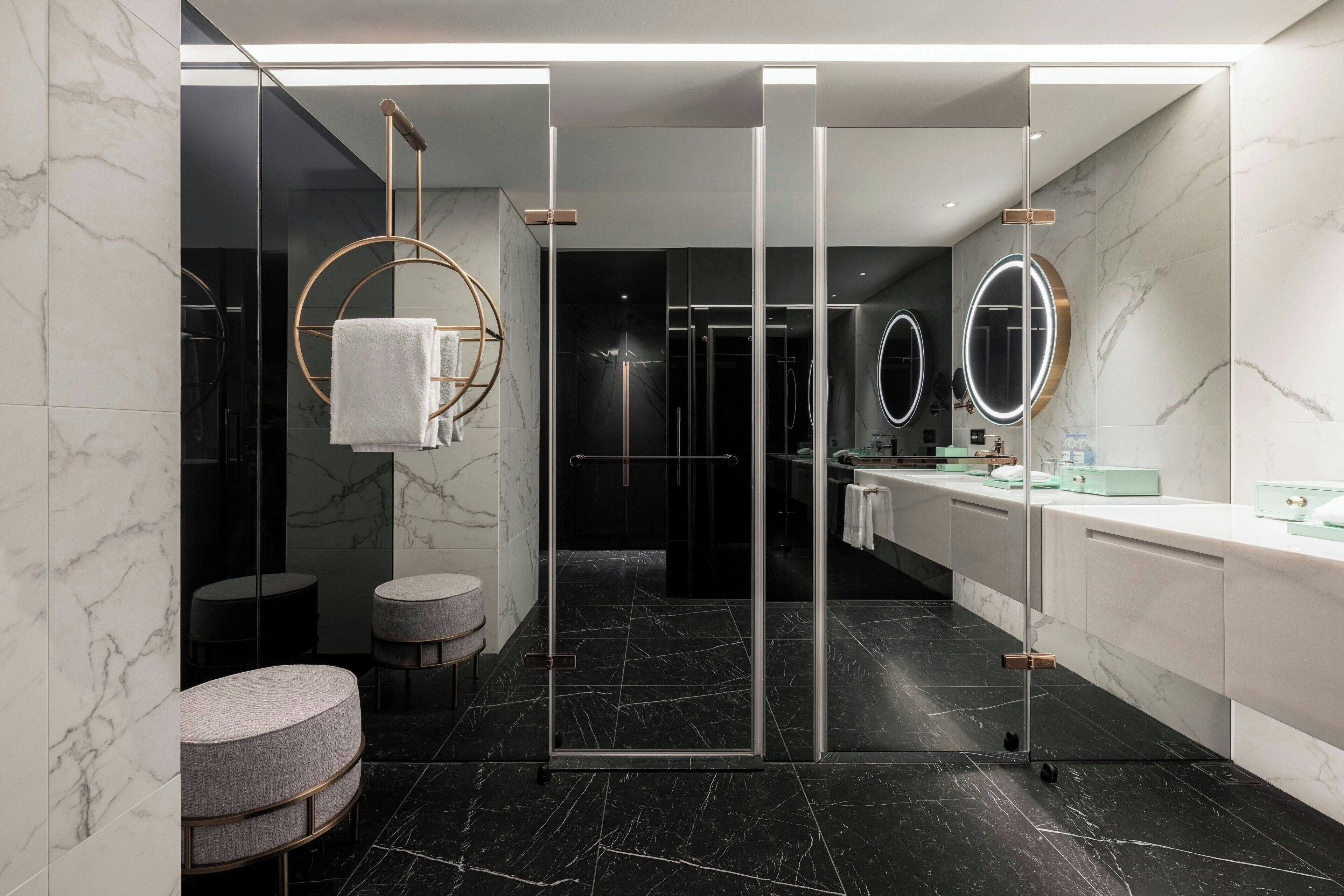 Un baño moderno con cabina de ducha de vidrio, suelo de mármol y tocador con espejo.