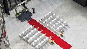 An outdoor wedding ceremony setup with white chairs arranged in rows, a red carpet, and floral decorations.