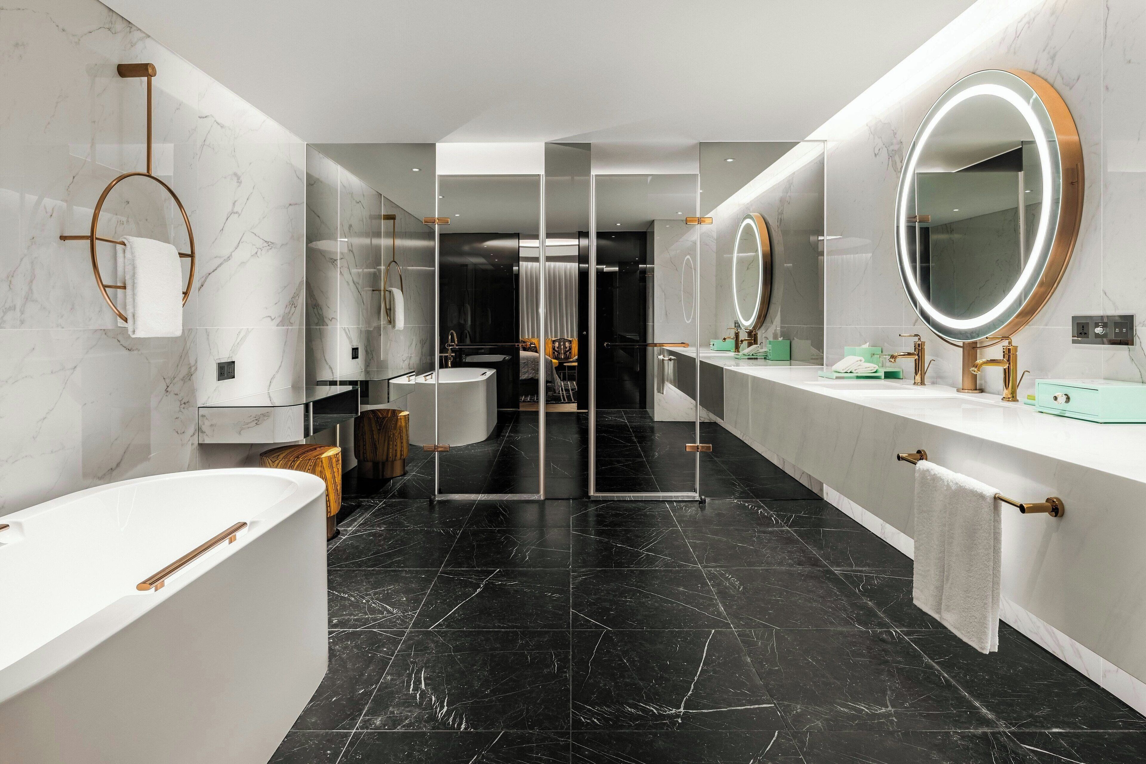 A modern bathroom with a large bathtub, two sinks, and a vanity with a mirror.