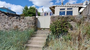 A stone staircase leading to a wooden gate, surrounded by dry grass and rocks.