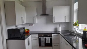A modern kitchen with white cabinets, a black countertop, a stove, and a sink.