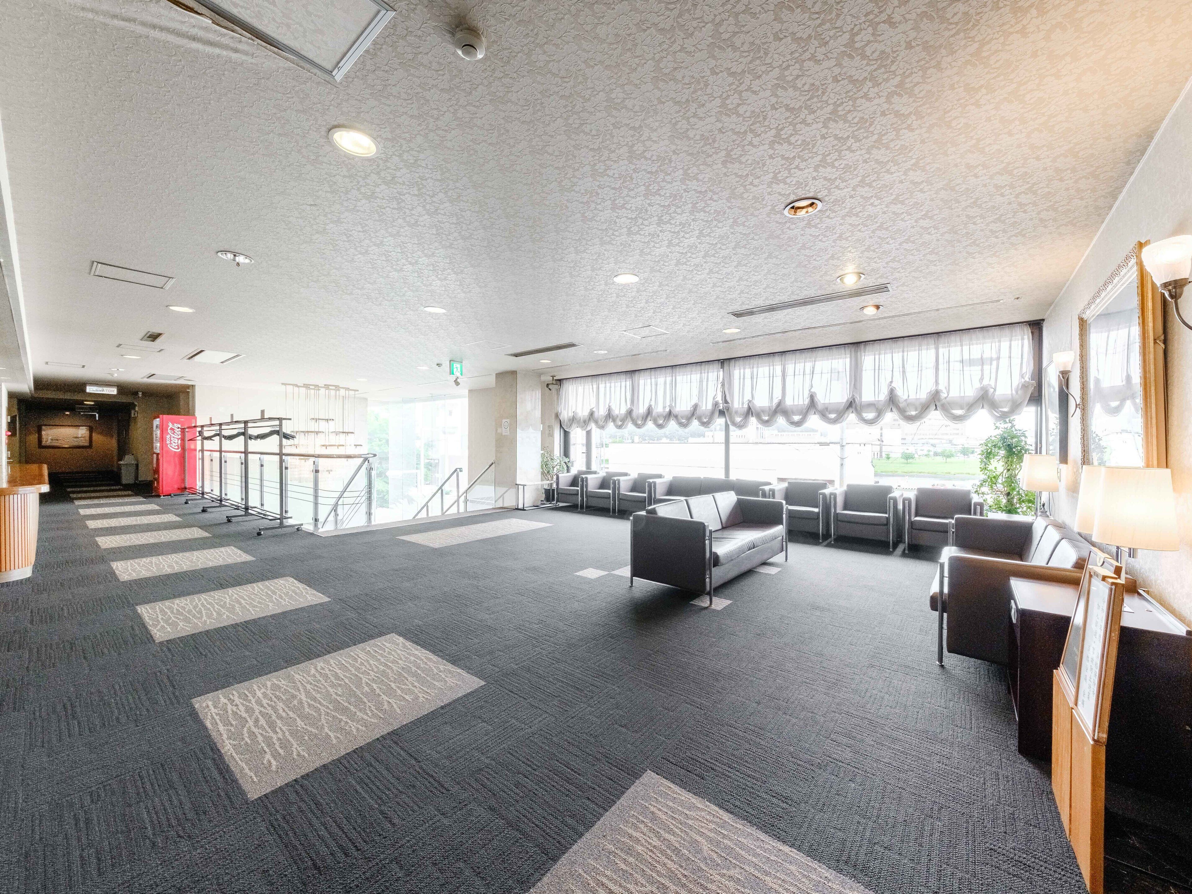 Een ruime lobby met een hoge plafond, een kamerbreed tapijt met patroon, een zithoek en grote ramen.
