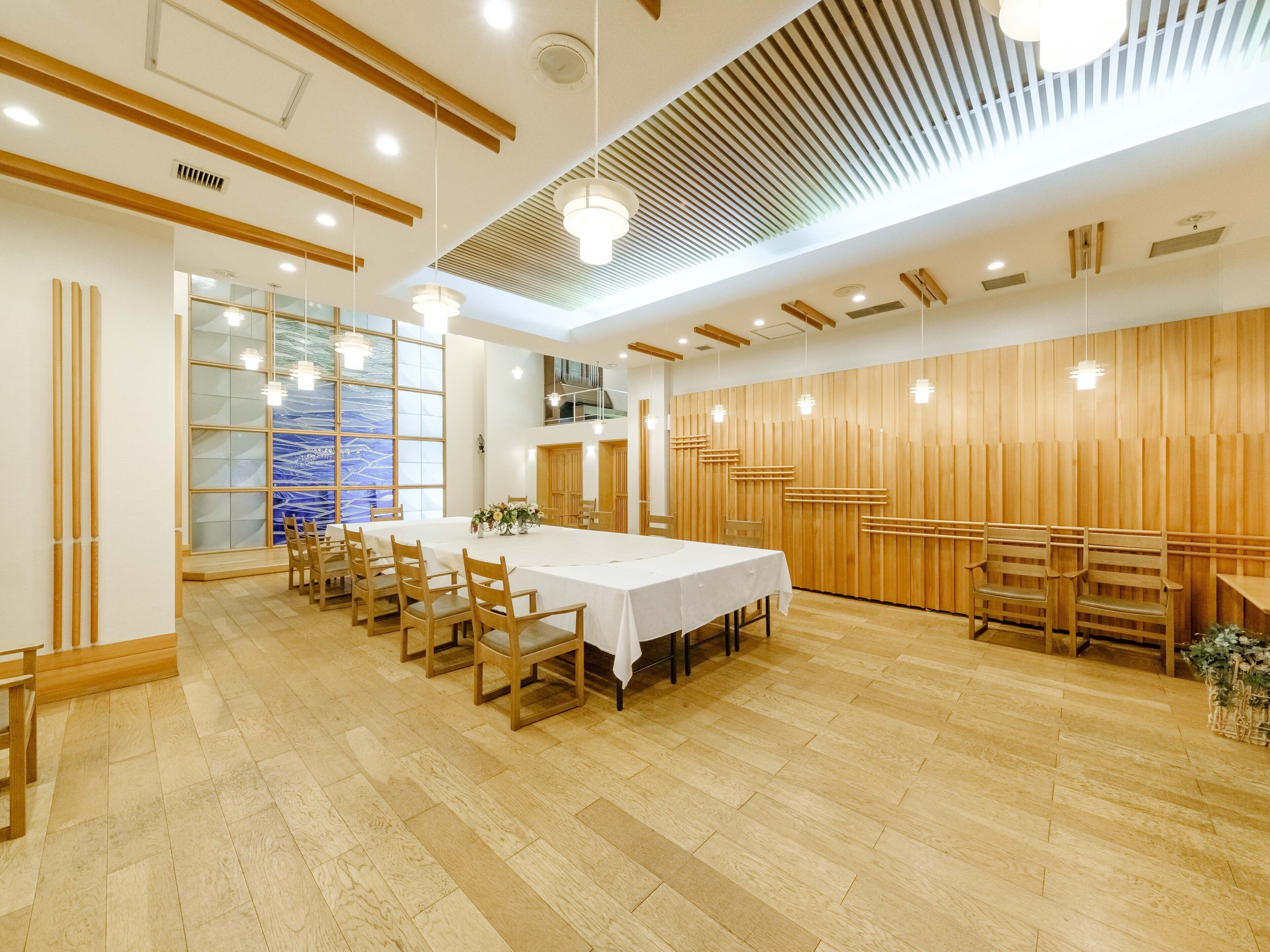 A spacious conference room with a long table, wooden chairs, and a modern ceiling design.