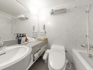 A modern bathroom with a white sink, toilet, and bathtub. There are hand soap dispensers, a tissue box, and a towel rack. - Tabist Abashiri Central Hotel (Abashiri)
