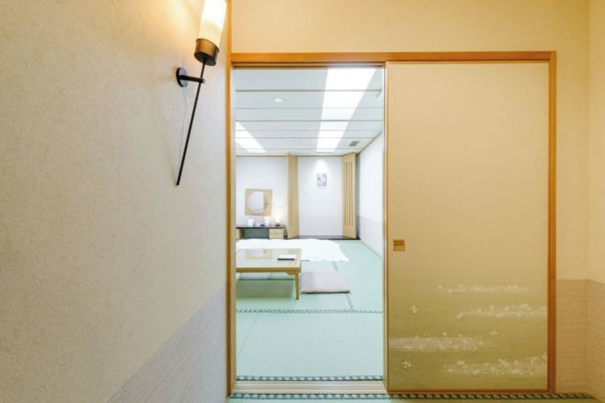 A traditional Japanese room with tatami flooring, a low wooden bed, and a sliding shoji screen door.
