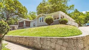 A two-story house with a stone retaining wall and a well-maintained lawn. - Sweet Sylvan Hills 3/2 - Ten Minutes to Airport (Atlanta)