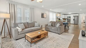 A modern living room with two grey sofas, a wooden coffee table, and a ceiling fan. - Sweet Sylvan Hills 3/2 - Ten Minutes to Airport (Atlanta)