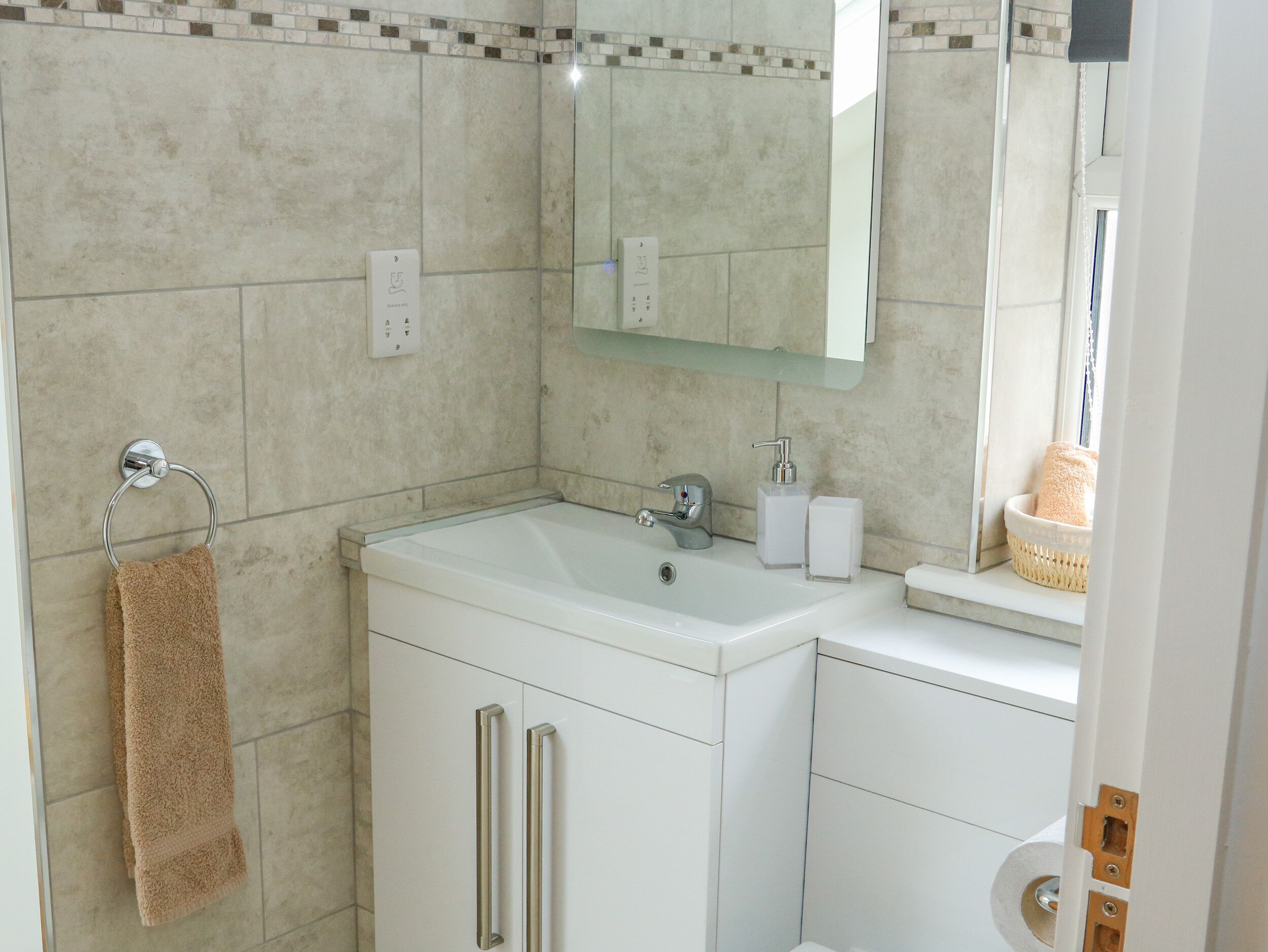 A modern bathroom with a white sink, mirror, and towel rack.