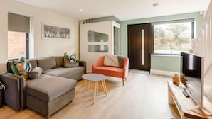 A modern living room with a grey sofa, a red armchair, and a small round table. - Roe Cottage - Disabled Adapted - 2 bed - hot tub (Alcester)