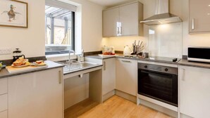 A modern kitchen with white cabinets, a built-in oven, a microwave, and a window providing natural light. - Fully Accessible-disabled Adapted-hot Tub-pets (Alcester)