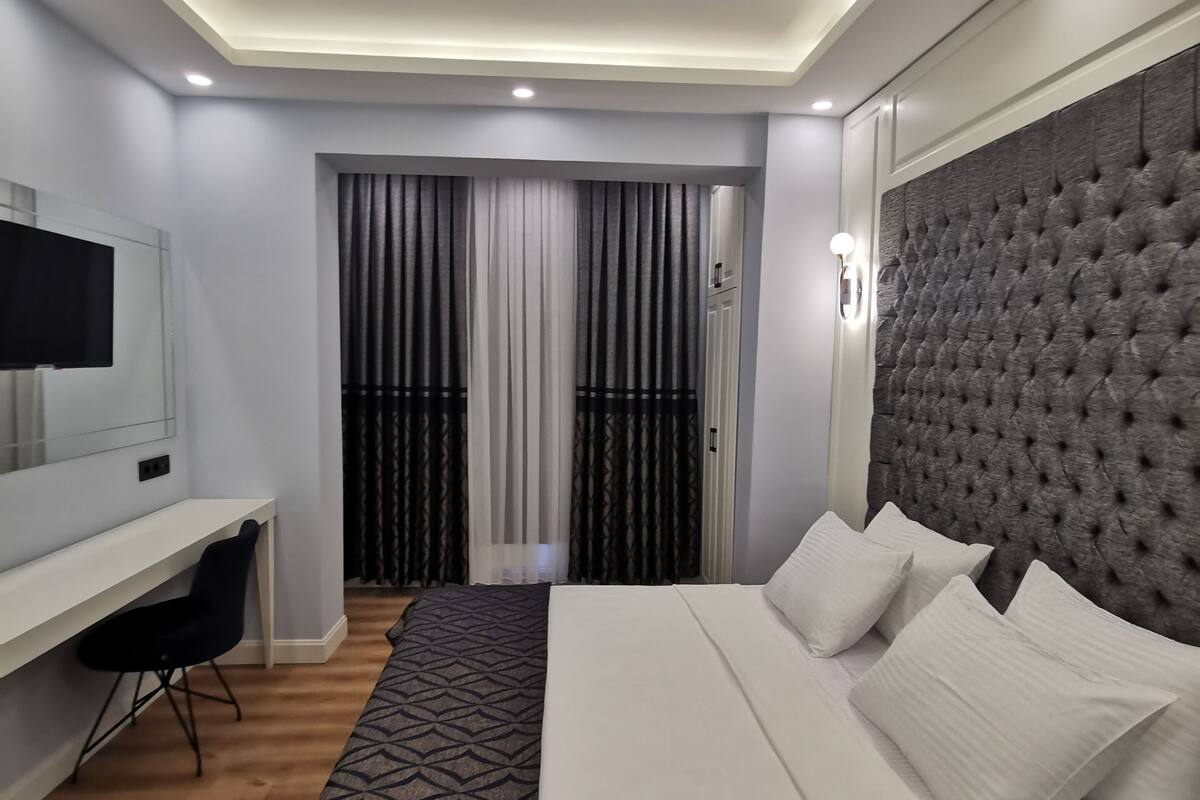 A modern bedroom with a bed, a desk, and a television.