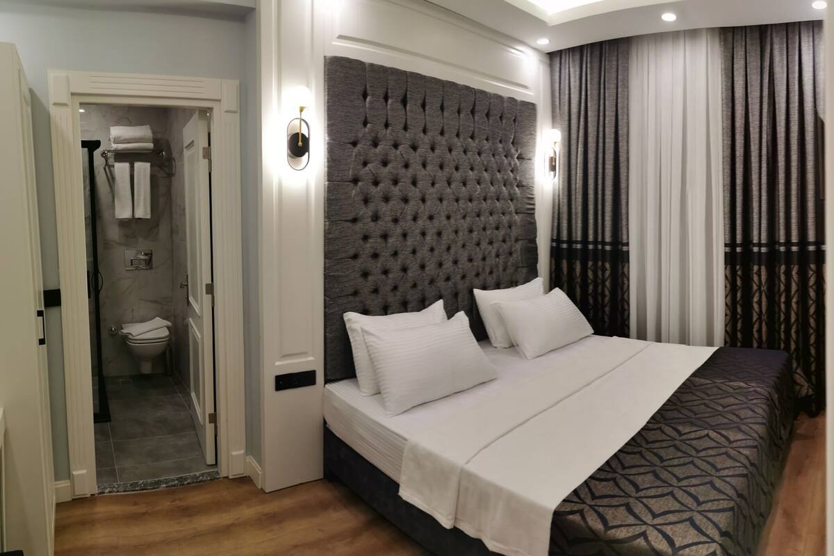 A modern hotel room with a large bed, a separate bathroom, and a curved ceiling design.