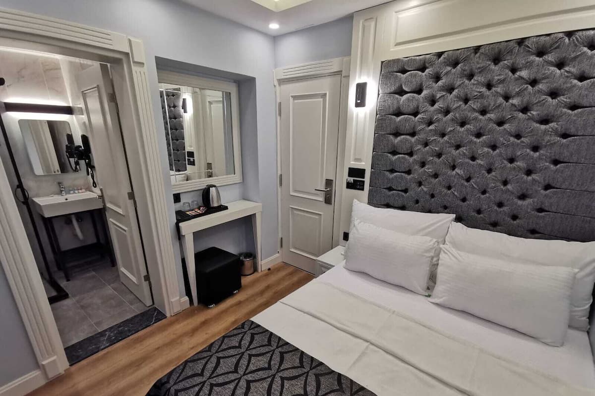 A modern hotel room with a large bed, a vanity with a mirror, and a tufted headboard.