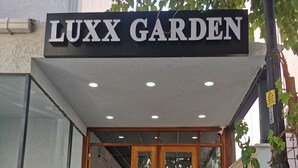 The entrance to LUXX GARDEN with a sign above the door, a staircase leading up, and a view into the interior. - LUXX GARDEN HOTEL (Istanbul)