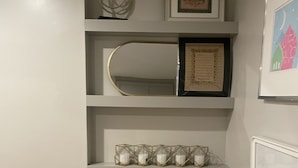 Un escalier avec des éléments en bois, des murs blancs et des étagères où sont disposés des objets décoratifs.